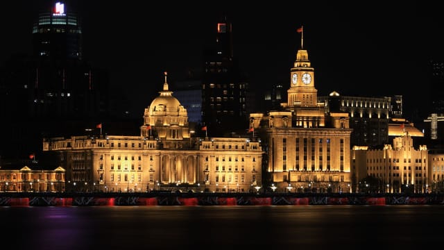 Night view of The Bund in Shanghai showcasing iconic historical buildings beautifully lit up.