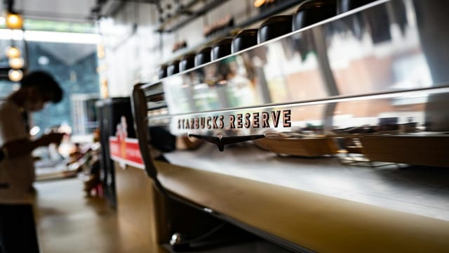 Contemporary Starbucks Reserve coffeeshop interior featuring a sleek espresso machine with a reflective surface.