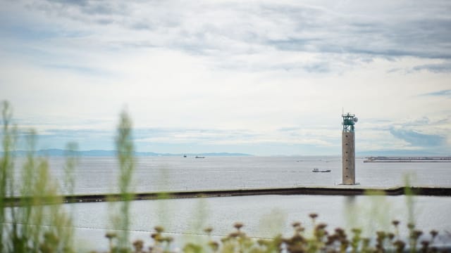 Concrete lighthouse overlooking the sea with cloudy skies in Osaka Bay, Japan.