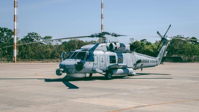 Military helicopter stationed at Brasília airstrip with clear blue sky background.