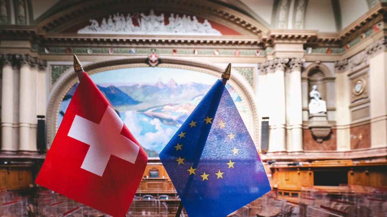 Swiss and EU flags inside the Swiss Parliament building in Bern, showcasing political unity.