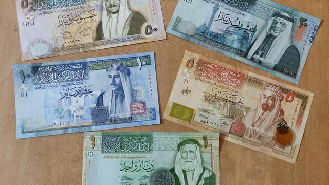 Collection of Jordanian dinar banknotes arranged on a wooden surface, showcasing currency design.