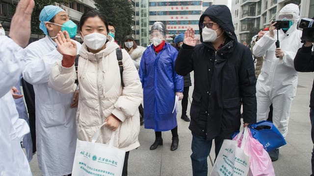 Healthcare workers and people in masks interacting outdoors during COVID-19 pandemic.