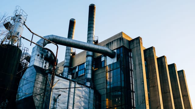 Illustrative image: Low angle exterior of factory located on city street under blue sky in evening time