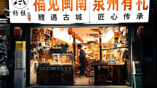 A bustling shopfront in a street market in Quanzhou, vividly lit and filled with local goods and lanterns.
