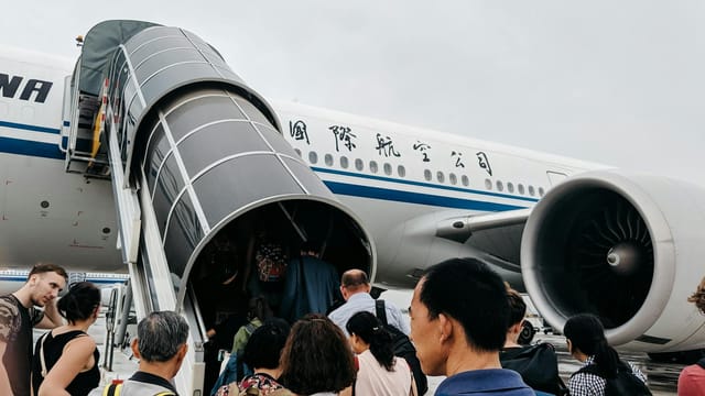A group of people boarding an airplane via a jet bridge at Beijing Airport, China.