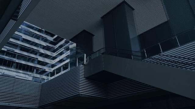From below of modern building with glass and concrete walls and stairs with metal railings on dark day