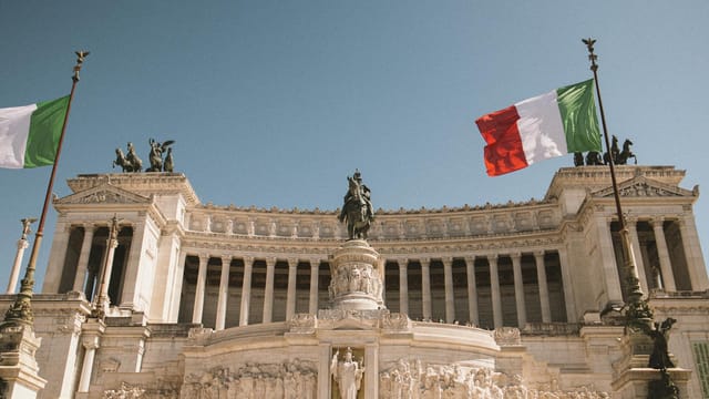 The iconic Vittorio Emanuele II Monument with Italian flags in Rome.