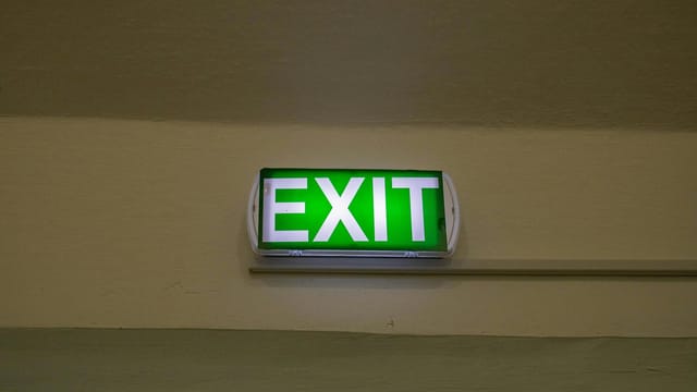 Bright green exit sign mounted on a hallway wall, offering clear direction for emergency evacuation.