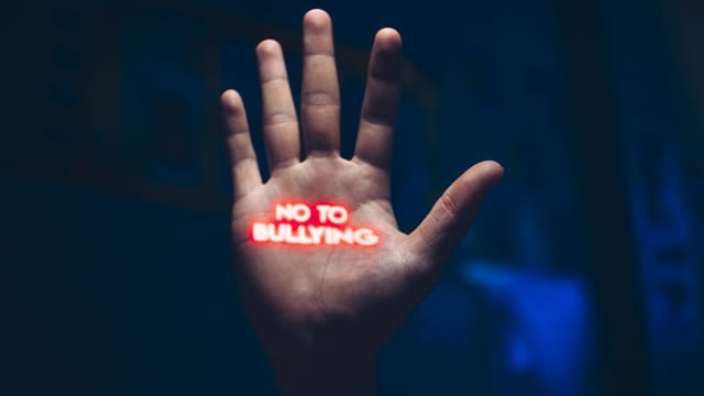 A hand with a glowing 'No to Bullying' message, highlighting bullying awareness.
