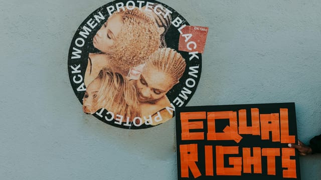 A mural advocating for black women's rights alongside a bold 'Equal Rights' sign.