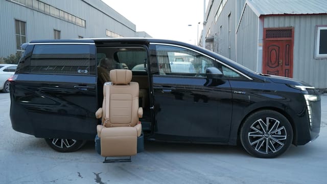 Black minivan parked outdoors with open door displaying an accessible seat feature on a cold winter day.