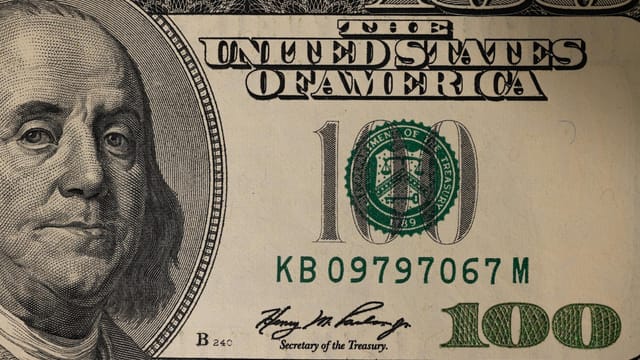 Detailed close-up image of a US one hundred dollar bill showing Benjamin Franklin.