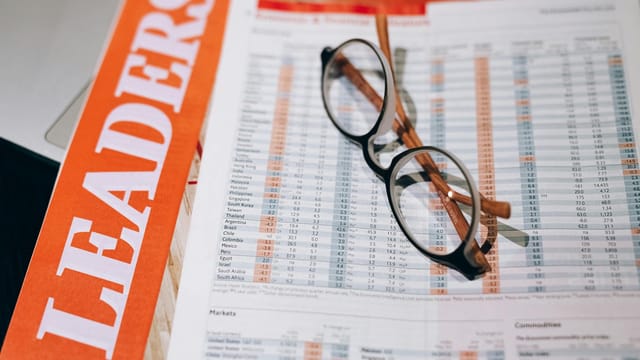 Close-up of financial documents with eyeglasses, depicting data analysis and business insights.
