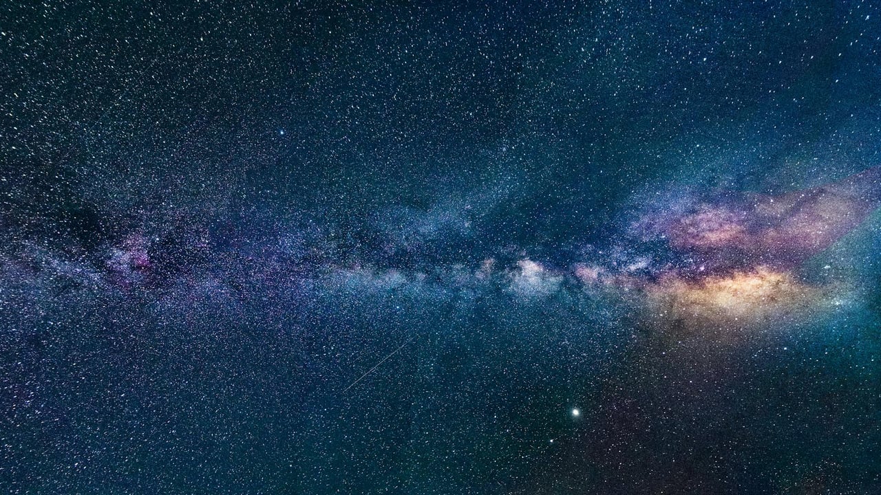 Capture of the Milky Way galaxy stretching across the dark night sky, filled with stars.