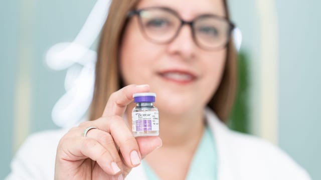 A woman holding a Botox vial, highlighting aesthetic medical cosmetics and beauty treatment.