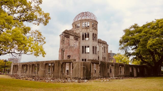 The iconic Hiroshima Genbaku Dome, a UNESCO World Heritage Site, set amidst spring foliage.