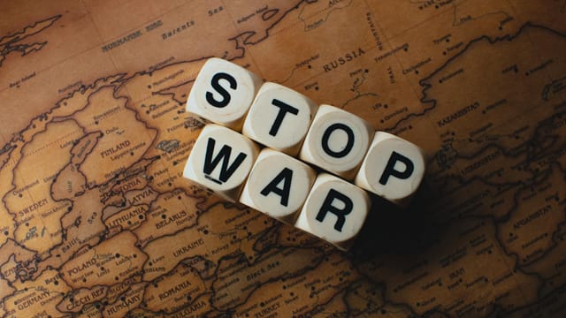 Dice with 'STOP WAR' on a vintage world map signifies peace.