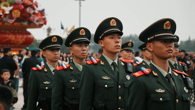 A group of soldiers in green uniforms marching outdoors, part of a ceremonial parade.