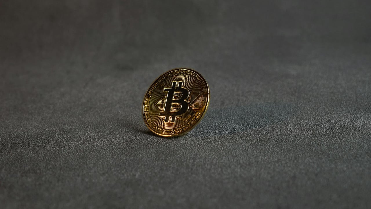 Close-up image of a golden Bitcoin standing on a grey surface, symbolizing cryptocurrency and digital finance.
