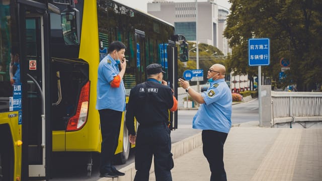 Traffic officers in uniform coordinate buses in bustling Beijing streets.