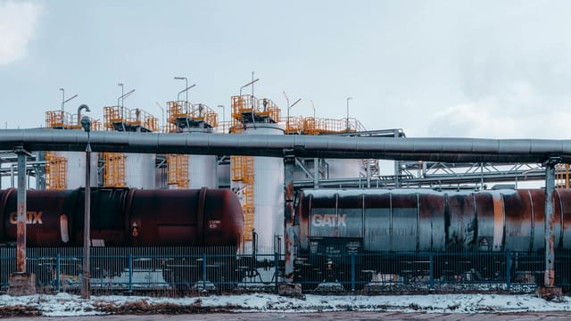 A winter scene of trains and industrial tanks in Trzebinia, Poland, highlighting the energy sector.