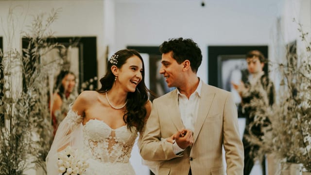 A joyful bride and groom pose for wedding photography inside a beautifully decorated venue.
