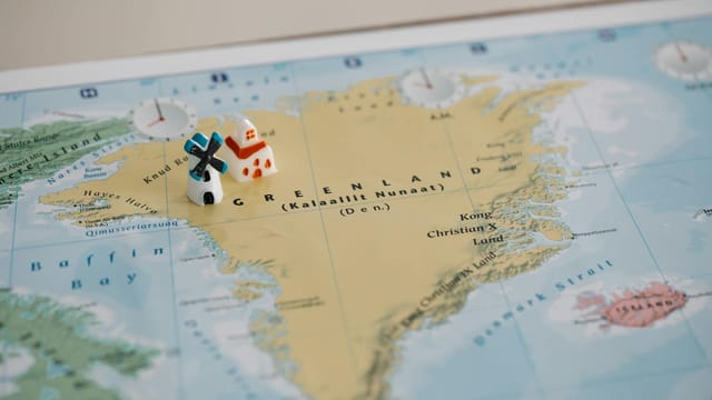 Toy houses on a detailed map of Greenland, highlighting geographic features. Ideal for travel concepts.