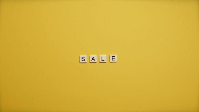 Single word 'SALE' spelled with tiles on a bright yellow background, ideal for advertising.