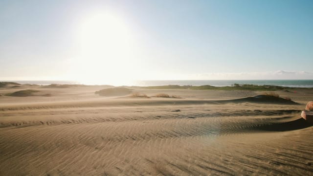 Breathtaking view of sandy dunes and ocean at sunset in Ilocos Region, Philippines.