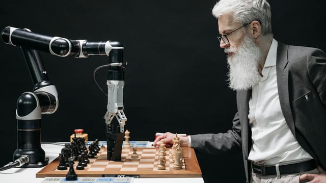 A man plays chess against an AI robotic arm, showcasing technology and strategy innovation.