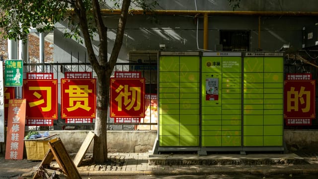 Bright green lockers beside advertising signs in a sunny urban street in Luoyang, China.