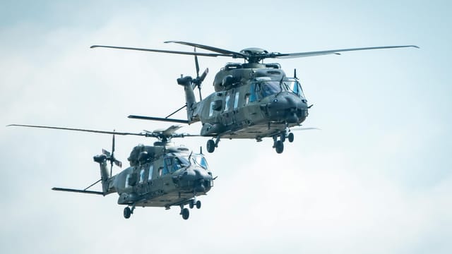 Two military helicopters flying in the sky, showcasing aviation technology.