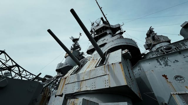 Close-up view of USS Alabama battleship's deck and cannons under a clear sky.