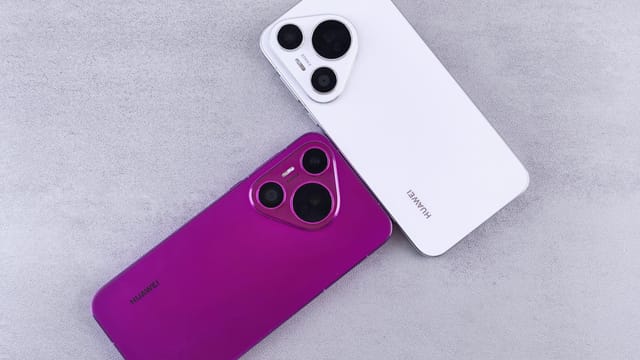 Two Huawei smartphones, one white and one purple, on a textured concrete surface.