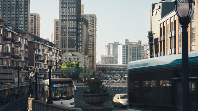 Dynamic city scene capturing buses and traffic amidst towering skyscrapers in daylight.