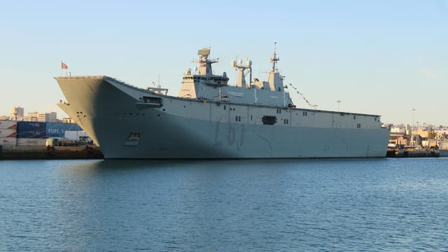 A naval ship moored at a dock in clear, sunny conditions at El Puerto de Santa María.