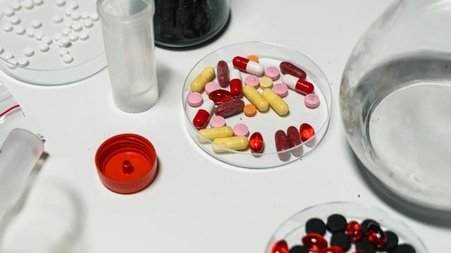 Assorted pills and capsules arranged on a lab table, emphasizing pharmacology and medicine.