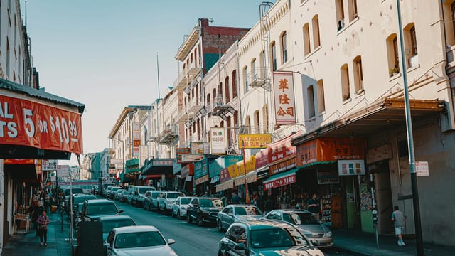 Vibrant urban scene in Chinatown featuring shops, signs, and cars in a busy street.