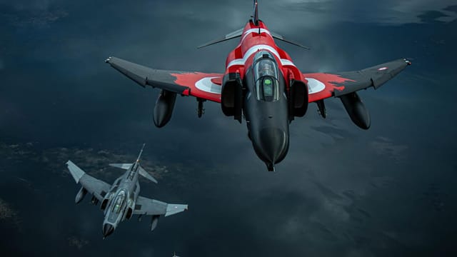 Three jet fighters soar through the sky in a dramatic aerial formation, showcasing their power.