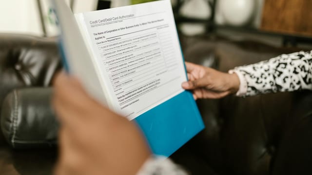 Close-up of a person examining a credit card authorization form inside an office setting.