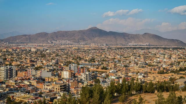 Aerial cityscape of Kabul, Afghanistan with mountains in the background.