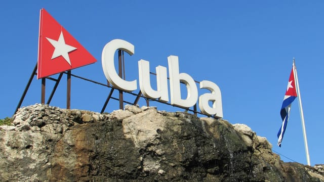 Cuba sign and flag against a clear blue sky in Havana, Cuba.