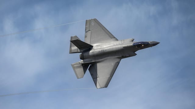 Aerial view of an F-35 fighter jet soaring in a clear blue sky above Kernville, California.