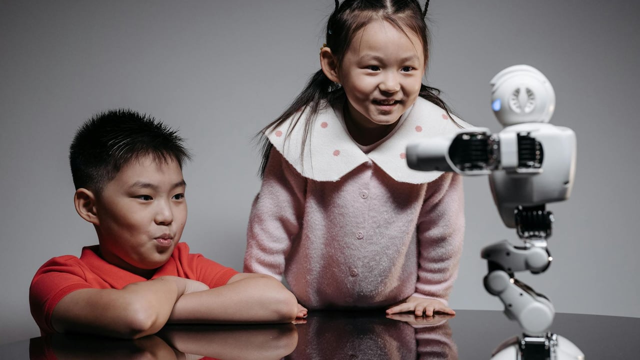 Two children interacting with a small robot, showcasing innovation and technology in a playful setting.