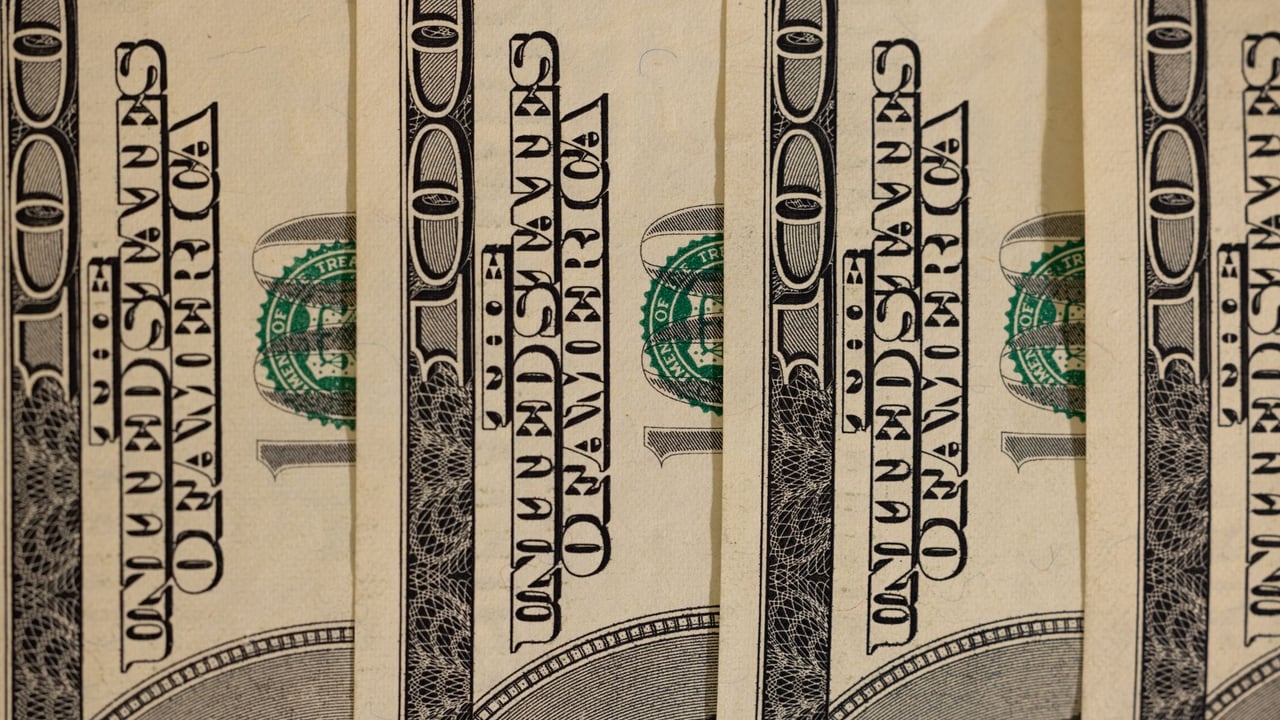 Detailed close-up of multiple US hundred dollar bills, showcasing currency design.