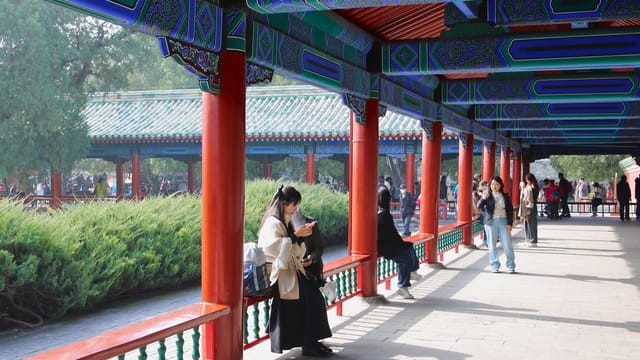 A vibrant corridor with traditional Chinese architecture in a Beijing park.
