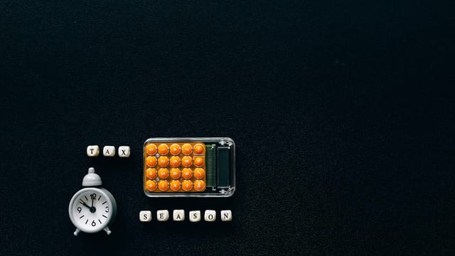 Flat lay of a tax season theme with a clock and calculator on a dark background.