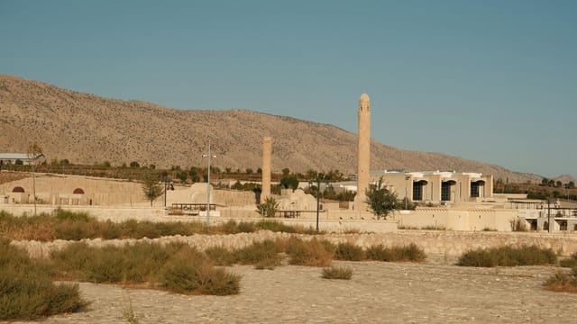 Scenic view of ancient Hasankeyf architecture with minarets against a mountain backdrop.