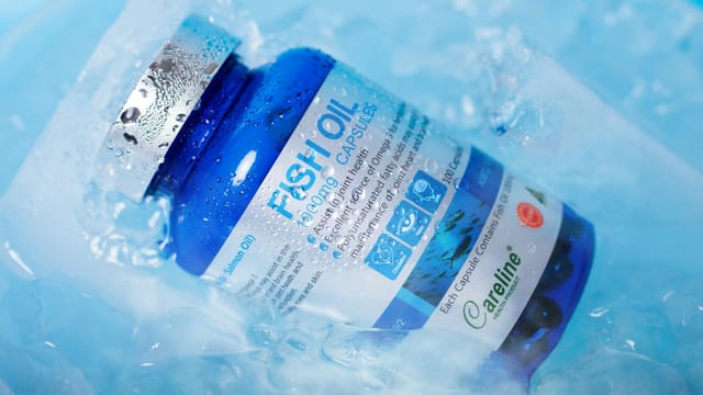 Blue bottle of fish oil capsules nestled in ice, emphasizing freshness and health benefits.